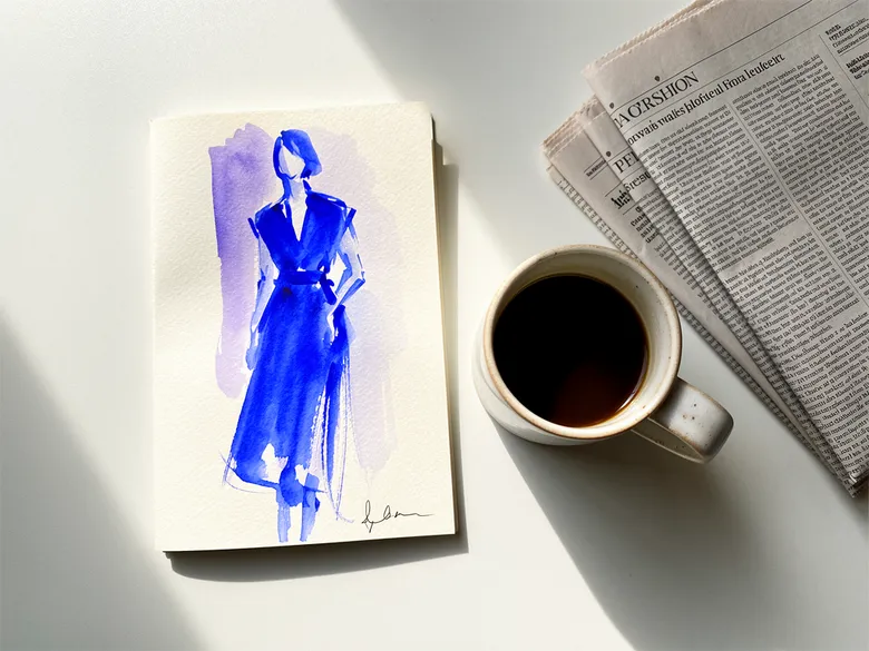 Akvarel af modeskitse, kaffekop og avis